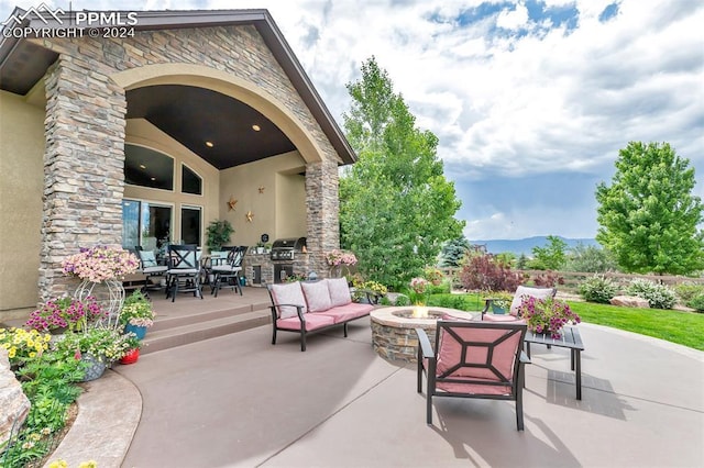 view of patio / terrace with a mountain view, area for grilling, and an outdoor living space with a fire pit