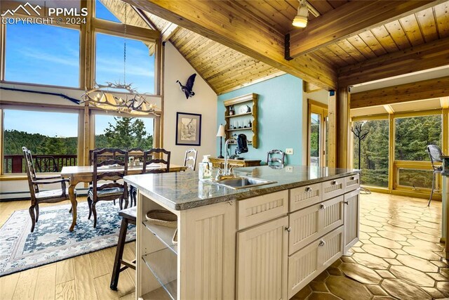 kitchen with a wealth of natural light, wooden ceiling, beam ceiling, and a kitchen island with sink