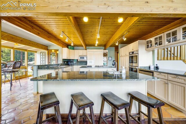 kitchen featuring a kitchen breakfast bar, white microwave, beam ceiling, wood ceiling, and track lighting