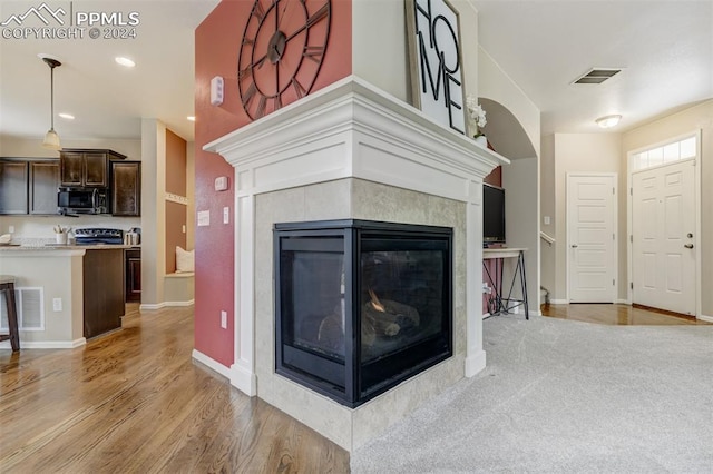 living room with a tile fireplace and light wood-type flooring