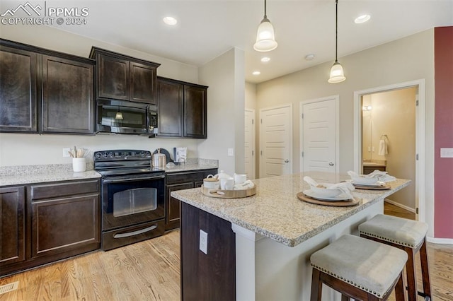 kitchen featuring a center island, light hardwood / wood-style floors, hanging light fixtures, and black appliances