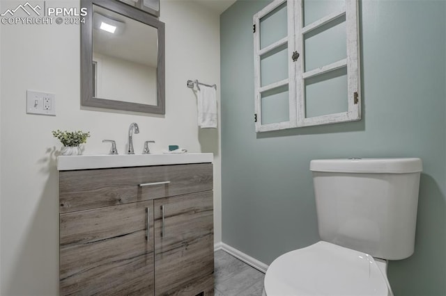 bathroom with vanity, toilet, and hardwood / wood-style floors