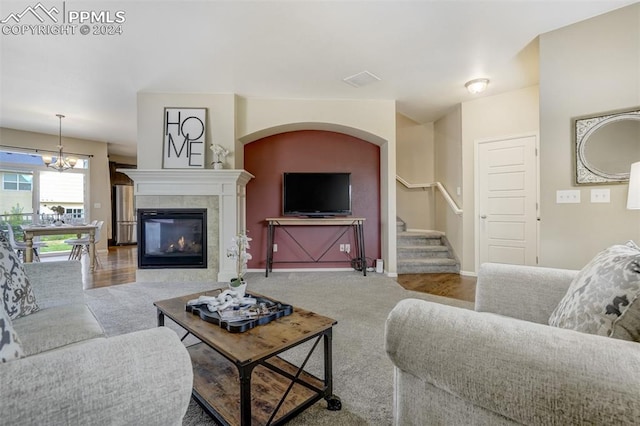 living room featuring an inviting chandelier, a tiled fireplace, and carpet floors