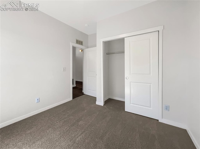 unfurnished bedroom featuring a closet and dark colored carpet