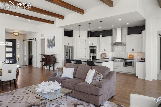 living room with a barn door, dark hardwood / wood-style flooring, and beamed ceiling