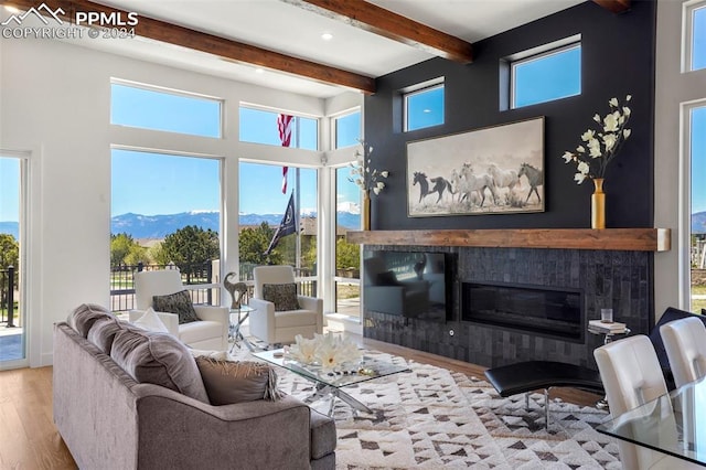 living room with a mountain view, beam ceiling, and light hardwood / wood-style flooring