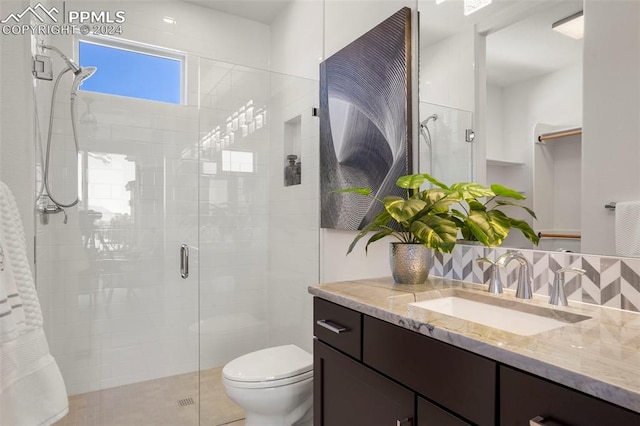 bathroom with vanity, tasteful backsplash, toilet, and a shower with shower door