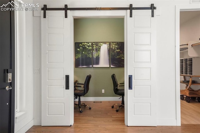 home office featuring hardwood / wood-style flooring and a barn door