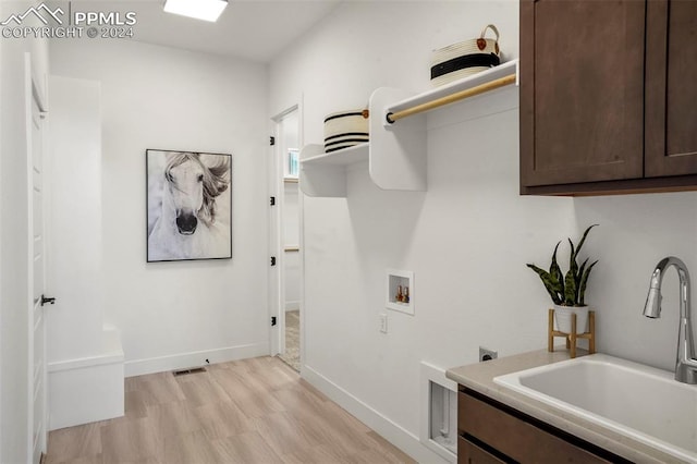 laundry area with cabinets, hookup for a washing machine, hookup for an electric dryer, sink, and light hardwood / wood-style flooring