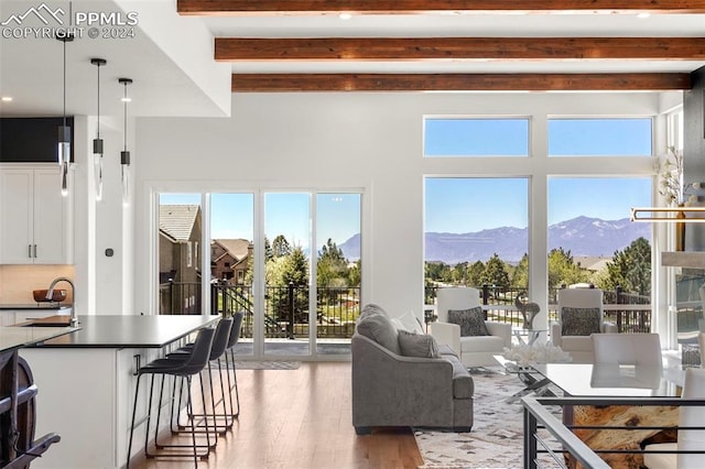 living room with a mountain view, hardwood / wood-style floors, a wealth of natural light, and beamed ceiling