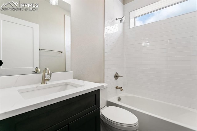 full bathroom featuring tiled shower / bath, toilet, and vanity