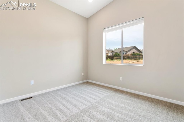 carpeted spare room featuring lofted ceiling