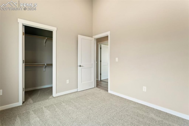 unfurnished bedroom featuring a closet, carpet floors, and a towering ceiling