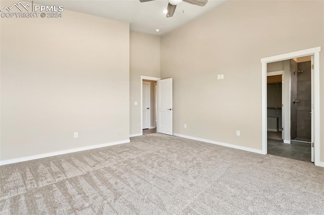 interior space with high vaulted ceiling, ceiling fan, a walk in closet, and dark carpet