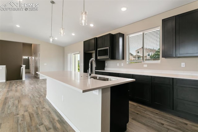 kitchen with wood-type flooring, hanging light fixtures, sink, a healthy amount of sunlight, and a kitchen island with sink