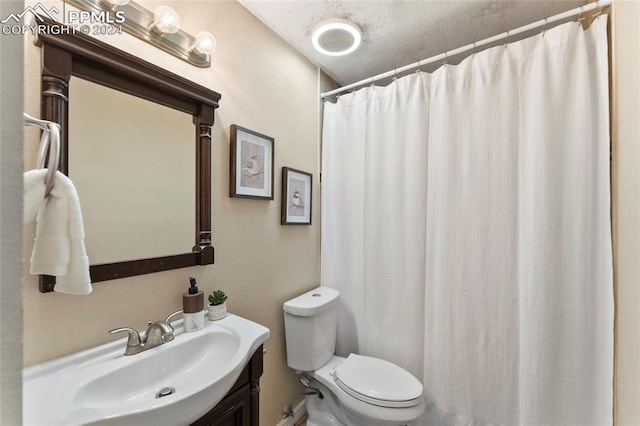 bathroom featuring a textured ceiling, vanity, and toilet