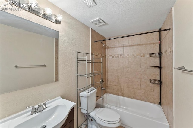 full bathroom featuring a textured ceiling, toilet, tiled shower / bath combo, and large vanity