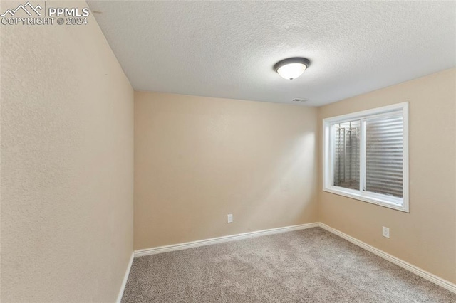 carpeted empty room featuring a textured ceiling