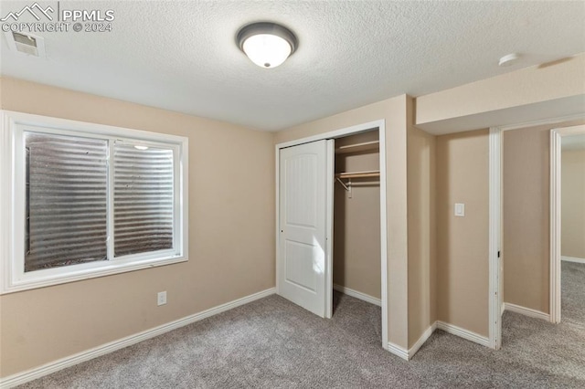 unfurnished bedroom featuring a textured ceiling, a closet, and carpet