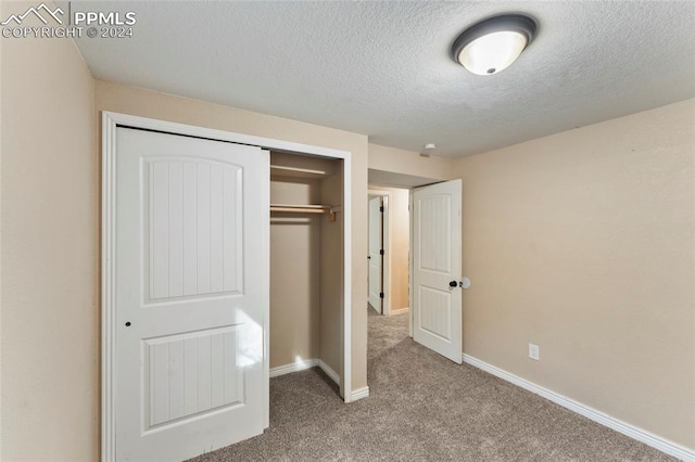 unfurnished bedroom featuring a textured ceiling, a closet, and carpet floors