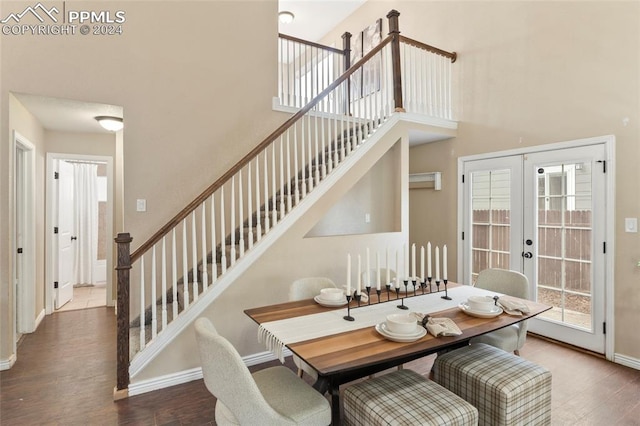 dining space with a high ceiling, hardwood / wood-style flooring, and french doors