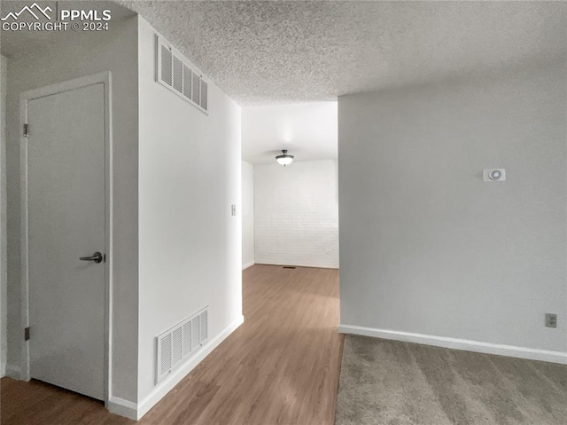 hall with a textured ceiling and hardwood / wood-style flooring