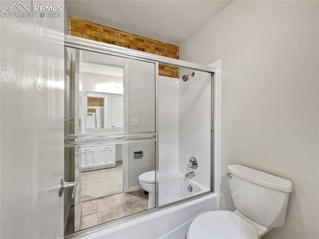 bathroom featuring tile patterned floors, toilet, and bath / shower combo with glass door