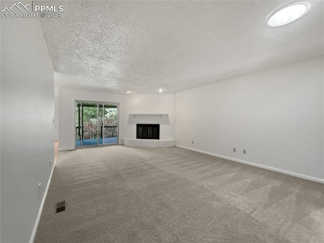 unfurnished living room featuring carpet flooring and a textured ceiling