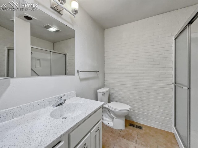 bathroom featuring tile patterned flooring, vanity, a shower with door, and toilet