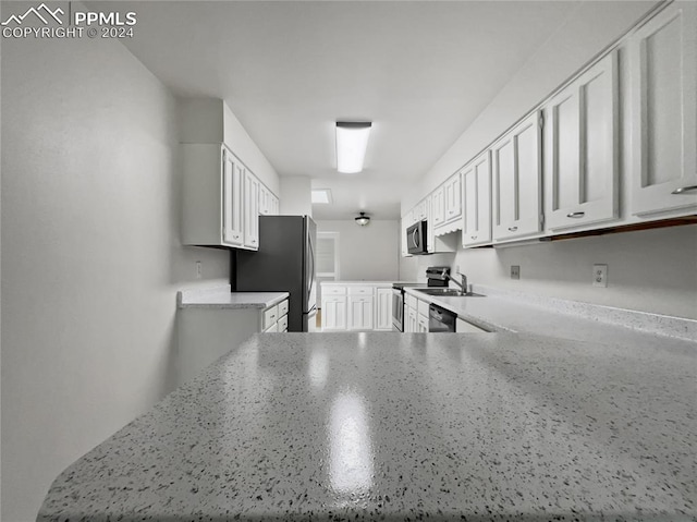 kitchen featuring appliances with stainless steel finishes, sink, white cabinetry, and light stone counters