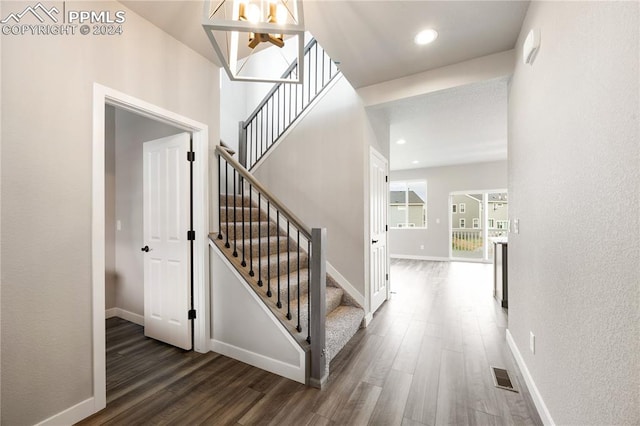 stairway with dark hardwood / wood-style flooring and a chandelier