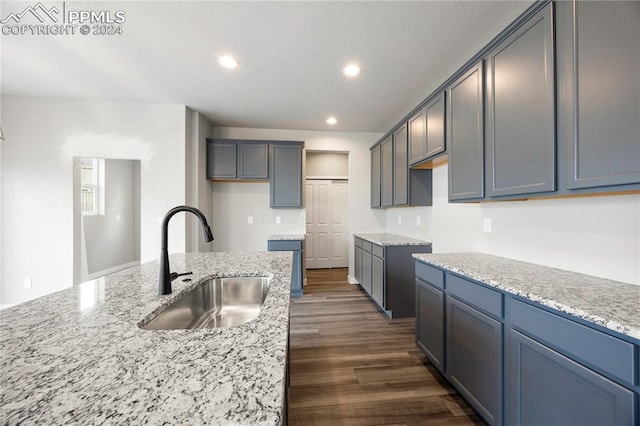 kitchen featuring dark hardwood / wood-style floors, light stone counters, and sink