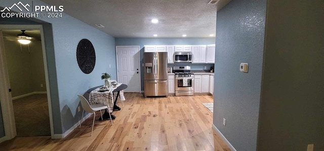 hallway with light hardwood / wood-style flooring and a textured ceiling