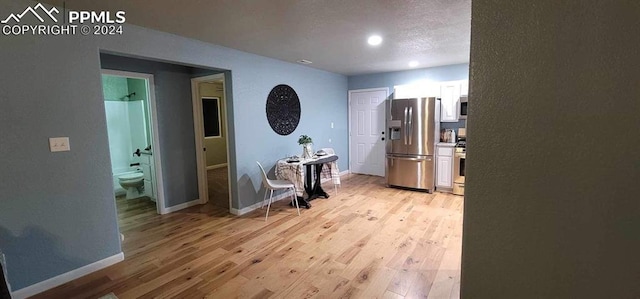 corridor with light hardwood / wood-style floors and a textured ceiling