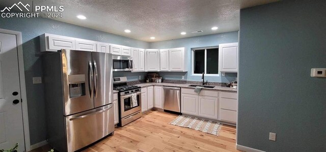 kitchen featuring white cabinets, a textured ceiling, stainless steel appliances, and sink