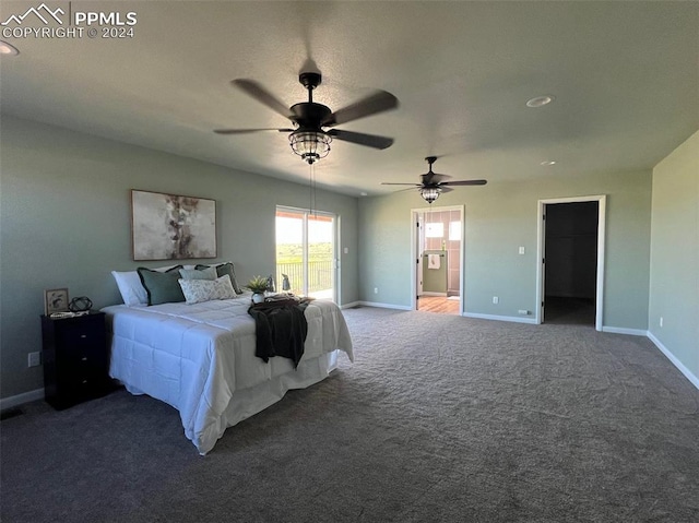 bedroom featuring connected bathroom, a spacious closet, dark carpet, and ceiling fan