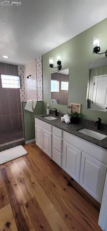 bathroom featuring a tile shower, vanity, a textured ceiling, and hardwood / wood-style flooring