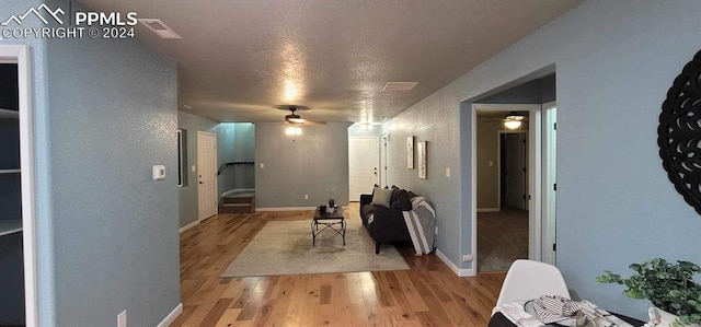 hallway with light hardwood / wood-style floors and a textured ceiling