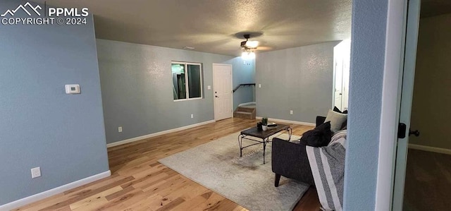 living room featuring a textured ceiling, light hardwood / wood-style flooring, and ceiling fan