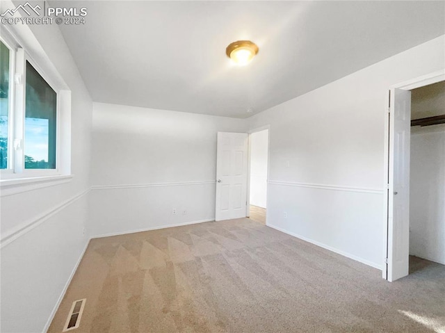 unfurnished bedroom with light carpet and a closet