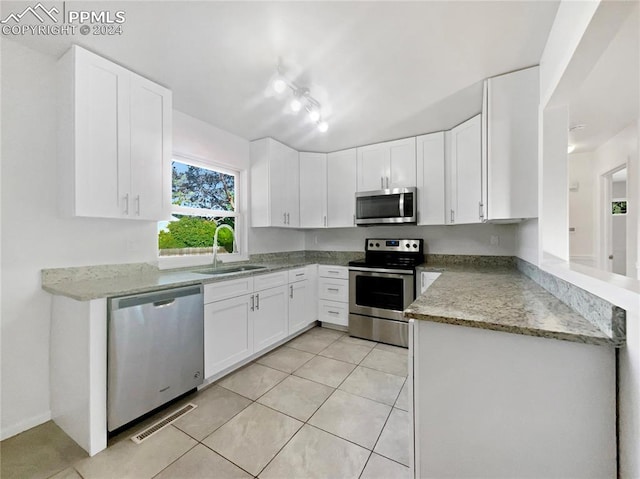 kitchen featuring white cabinets, sink, light tile patterned flooring, light stone counters, and stainless steel appliances