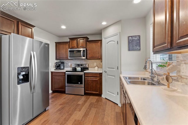 kitchen featuring sink, light wood-type flooring, stainless steel appliances, and tasteful backsplash