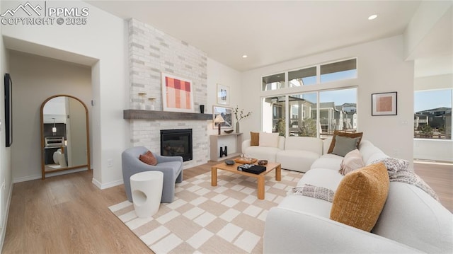 living room with a brick fireplace and light wood-type flooring