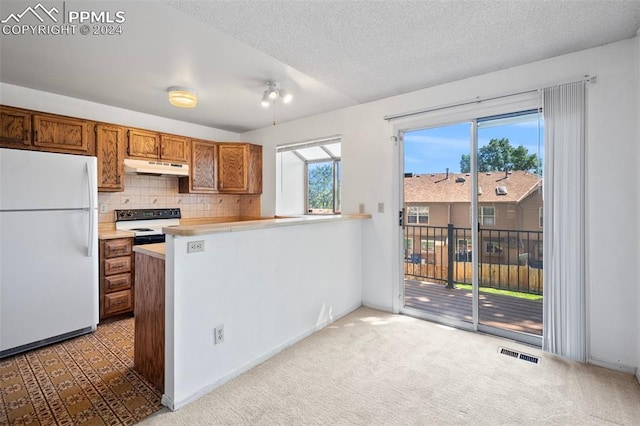 kitchen with kitchen peninsula, decorative backsplash, carpet floors, and white appliances