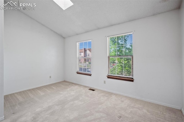 carpeted empty room with a textured ceiling and vaulted ceiling with skylight