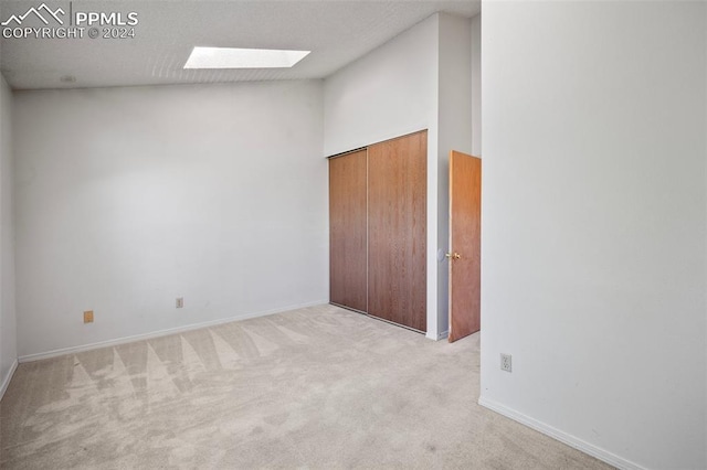 carpeted empty room with a high ceiling and a skylight