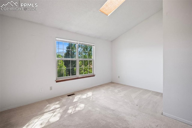 spare room featuring light carpet, a textured ceiling, and vaulted ceiling