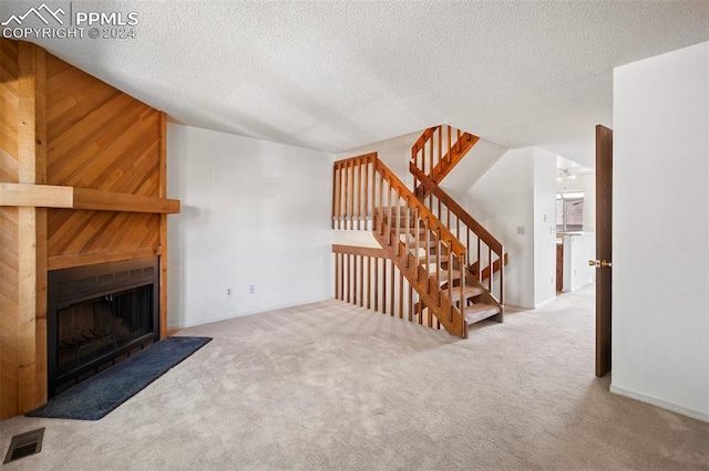 unfurnished living room featuring carpet, a textured ceiling, and wood walls