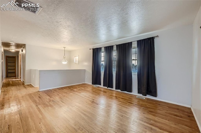 spare room with a textured ceiling and hardwood / wood-style flooring