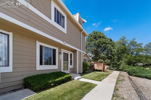 view of side of property featuring a lawn and a wooden deck